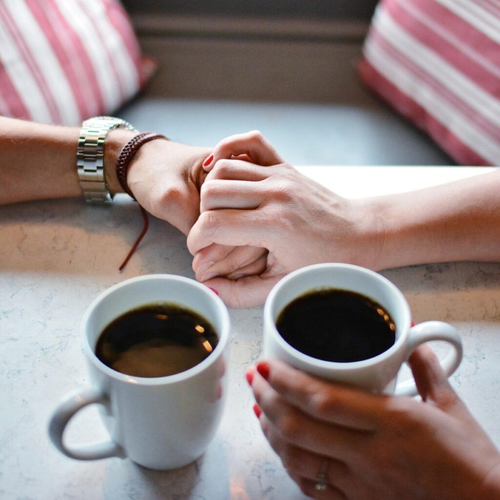 Questions for couples - Couple holding hands over coffee, sharing a warm conversation and emotional connection.
